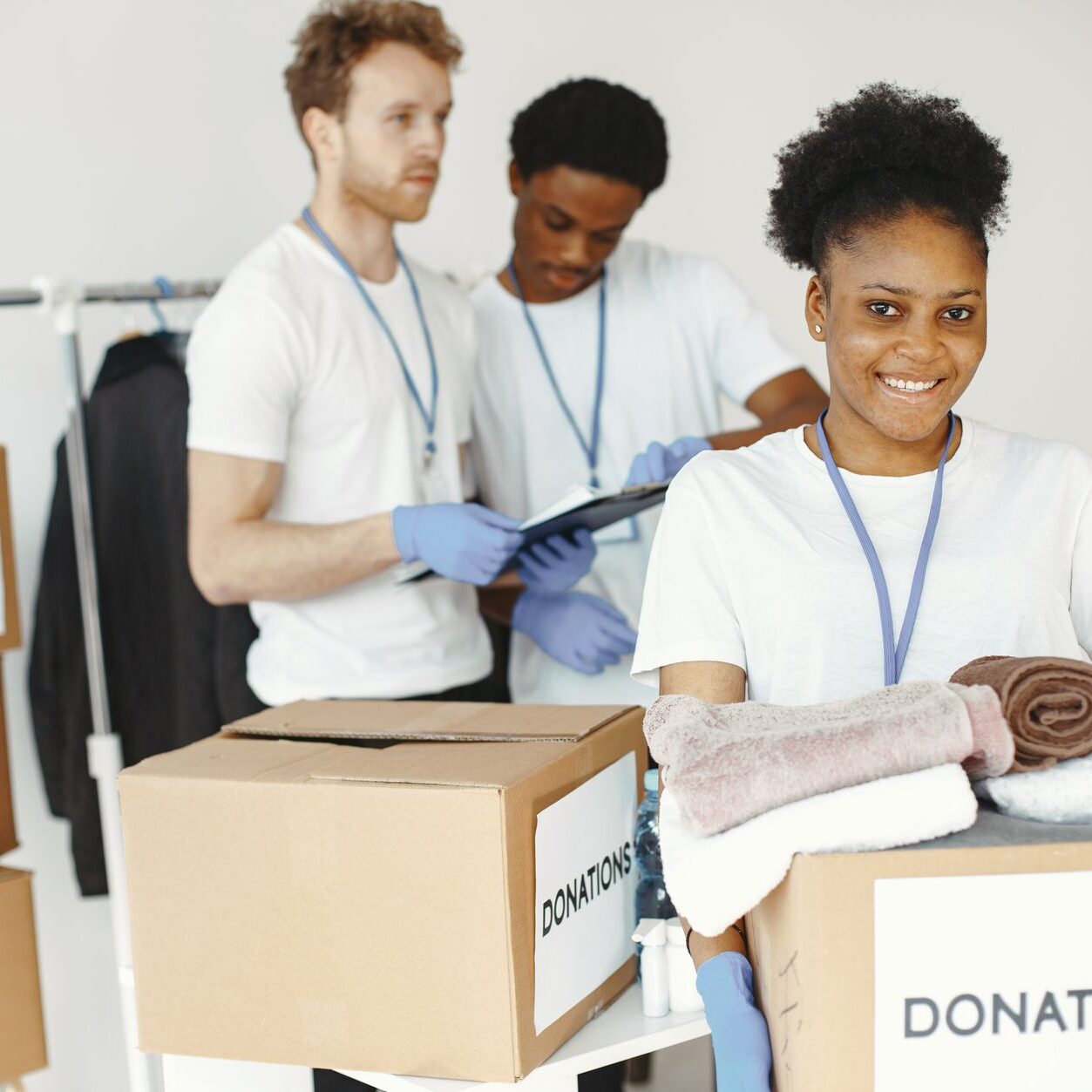 Group of volunteers smiling while sorting donation boxes indoors for a charity organization.